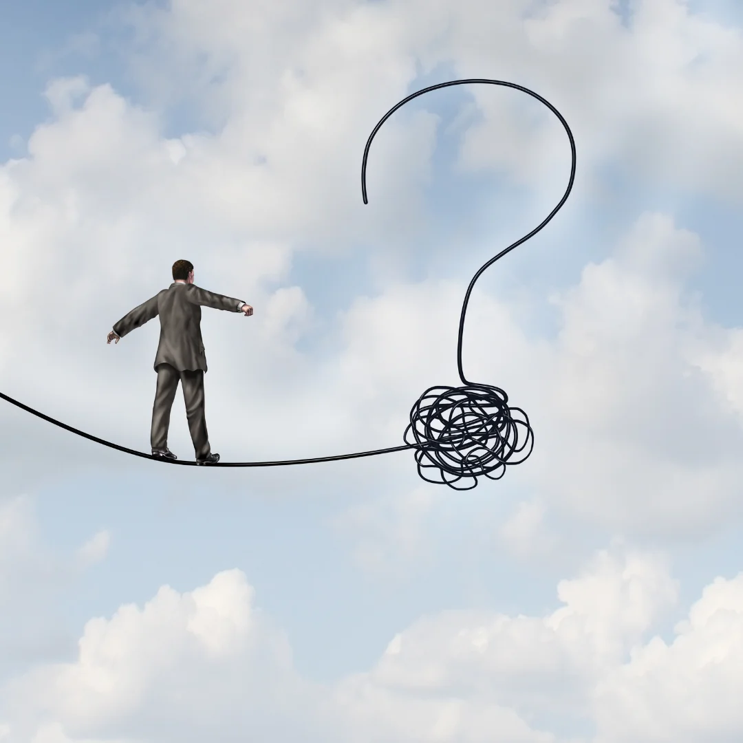 A man in a suit balances on a rope, with a large question mark hovering above him, symbolizing uncertainty.