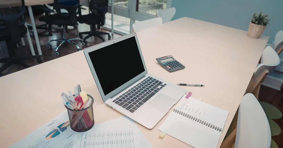 A laptop on a desk with a pen and notepad, symbolizing planning for Salesforce implementation costs.